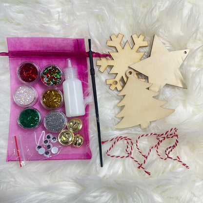 Crafting kit with wooden ornaments, glitter, and decorative items on a white textured background